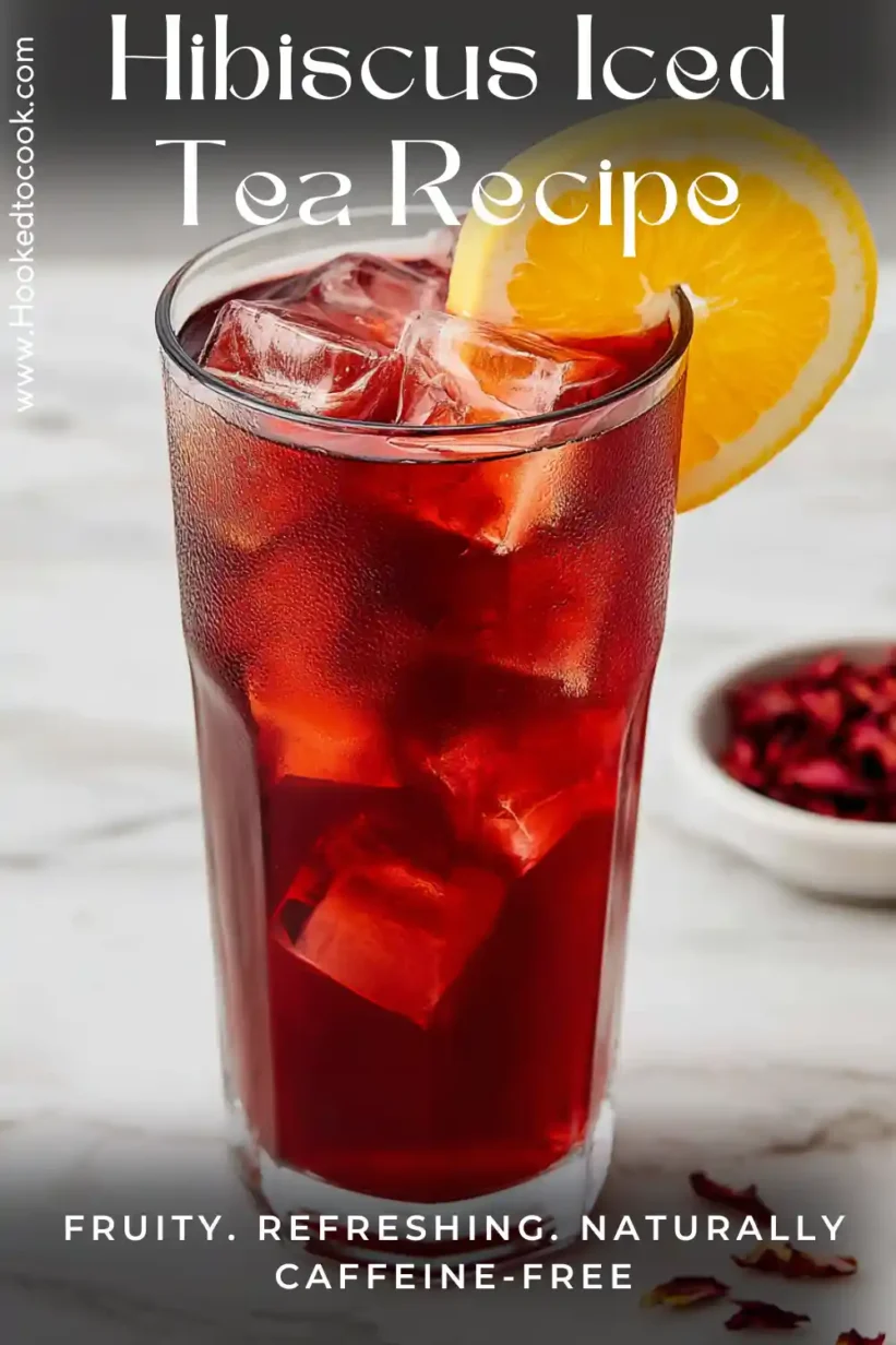 hibiscus iced tea in glass with ice cubes and orange slice