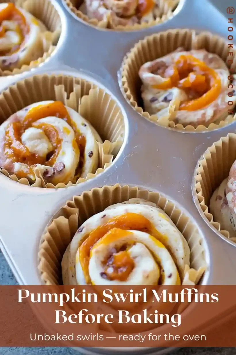 pumpkin cinnamon roll muffins unbaked spirals in muffin tin with pumpkin swirl, parchment liners