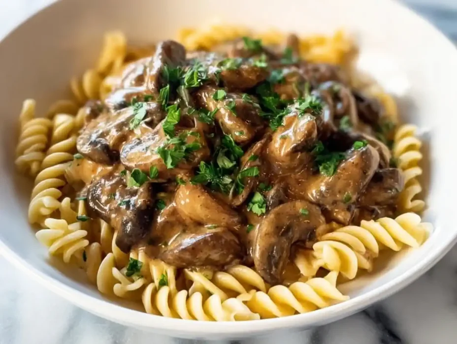 Creamy vegetarian mushroom stroganoff served in a bowl with herbs on top.