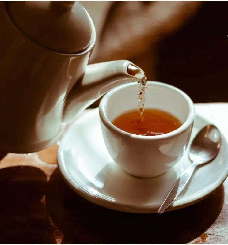 A steaming cup of soursop tea surrounded by fresh soursop fruit.
