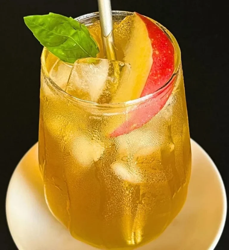 A refreshing glass of iced apple green tea with apple slices and ice