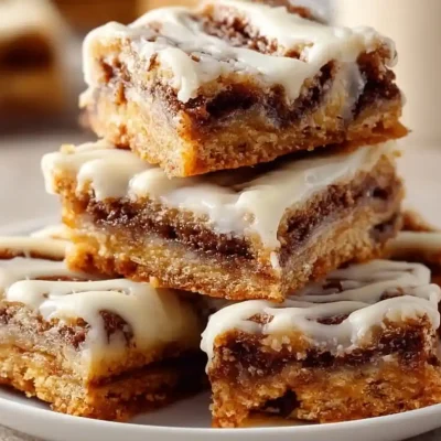 Delicious cinnamon roll bliss bars topped with icing on a rustic wooden table.
