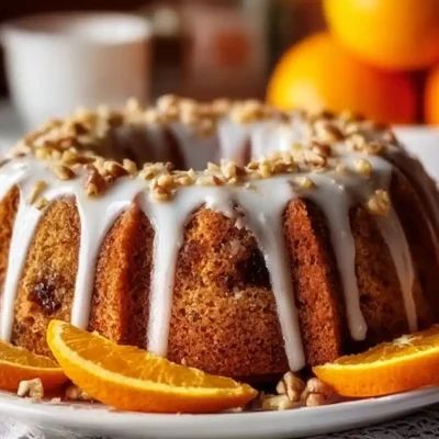 Date Walnut Orange Cake with glaze, sliced oranges, and chopped walnuts.