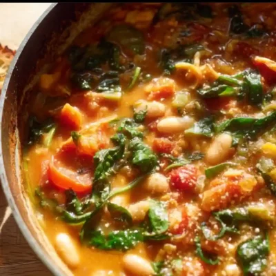 Creamy vegan tomato white bean stew served in a bowl with fresh herbs on top.