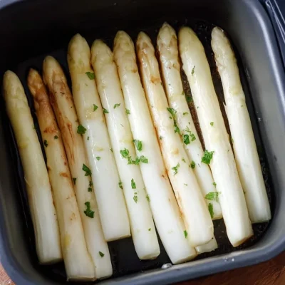 Air-fried white asparagus served on a plate garnished with herbs