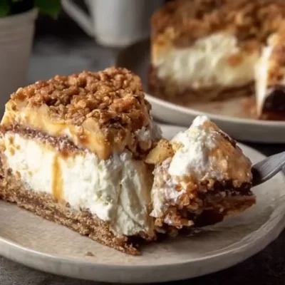 Apple Crumble Cheesecake slice with caramel drizzle on a plate and fork.