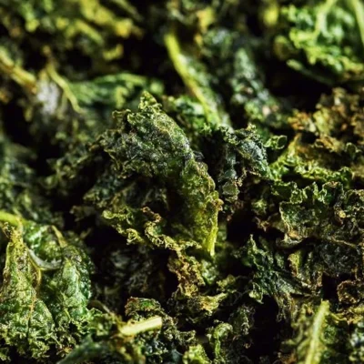 Baked kale chips served in a bowl topped with sea salt
