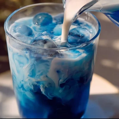 A refreshing glass of Butterfly Pea Tea with a vibrant color and garnished with lemon.