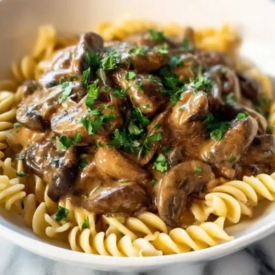 Creamy vegetarian mushroom stroganoff served in a bowl with herbs on top.