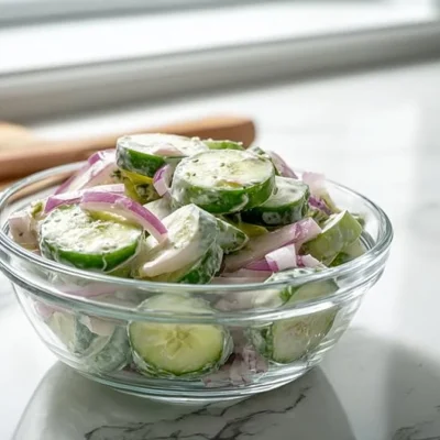 Fresh cucumber salad with herbs and dressing in a bowl.
