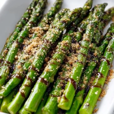 Flavorful asparagus drizzled with balsamic glaze on a white plate