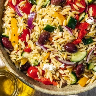 Colorful Greek Pasta Salad with vegetables and feta cheese in a bowl.
