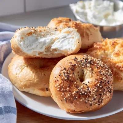 Freshly baked homemade bagels with toppings on a wooden board.