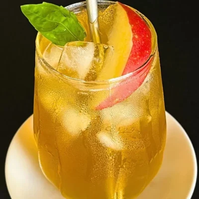 A refreshing glass of iced apple green tea with apple slices and ice