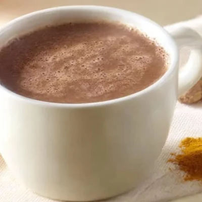 A cup of immunity boosting hot chocolate topped with whipped cream and cocoa.