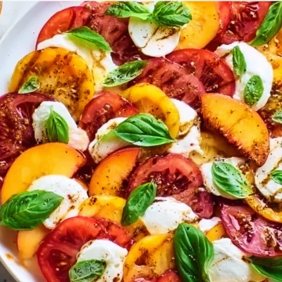 Colorful Peach Tomato Caprese Salad with fresh basil and mozzarella.