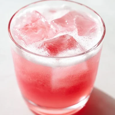 A refreshing glass of homemade rhubarb soda with ice and fresh rhubarb stalks.