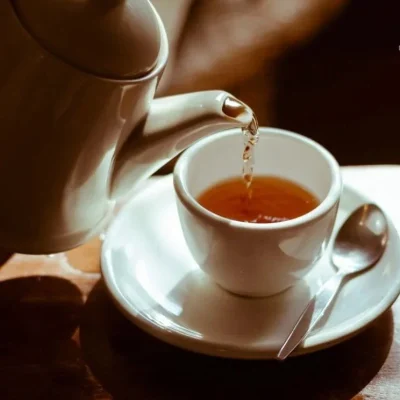 A steaming cup of soursop tea surrounded by fresh soursop fruit.
