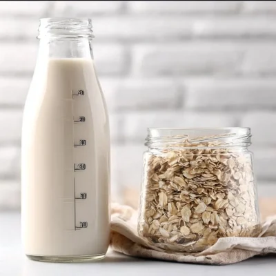 Creamy vanilla oat milk in a glass with ingredients in the background.
